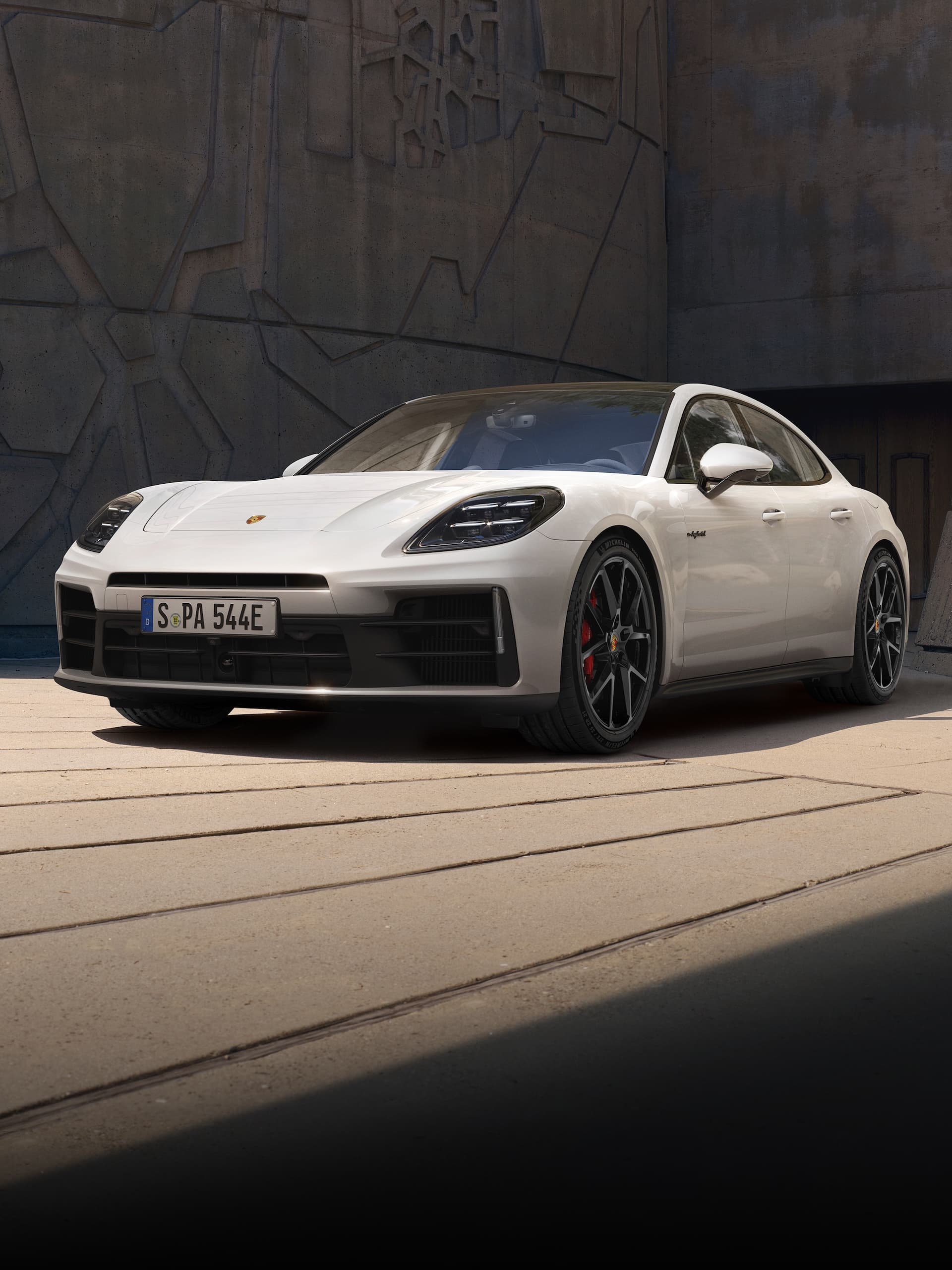 A Porsche Panamera parked in front of a modern building.